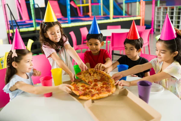一群快乐的孩子一边庆祝生日 一边吃着美味的披萨 在游戏室里玩得很开心 — 图库照片