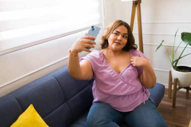 Romantik İspanyol kadın akıllı telefonuyla uzun mesafeli erkek arkadaşı için seksi bir fotoğraf çekiyor ve mesajlaşıyor. 