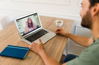 Neşeli bir adam kız arkadaşıyla konuşuyor ve sanal bir randevuda dizüstü bilgisayarına bakıyor ve şarap içiyor.