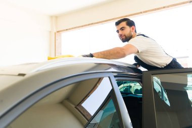 Profesyonel erkek işçi, araba yıkamada temizledikten sonra aracın suyunu kurutuyor.. 