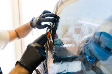 Erkek otomobil işçisi renkli film yüklüyor ve fazladan filmi bıçakla kesiyor.