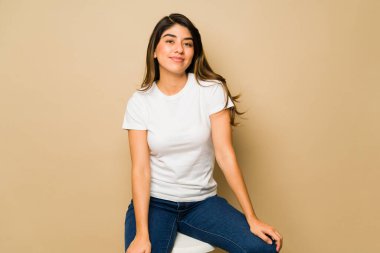 Stüdyo arka planında boş fotokopi alanı olan beyaz bir tişört giyen güzel İspanyol genç kadın.