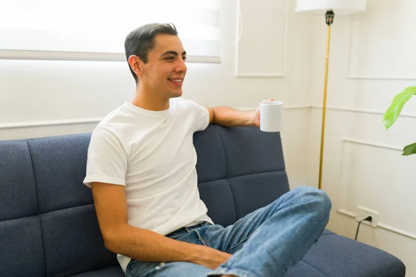 Rahatlamış Genç Adam Beyaz Bir Tişört Giyip Kahve Içerken Gülümsüyor — Stok fotoğraf