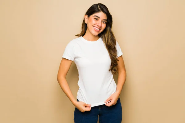 Atractiva Joven Latina Sonriendo Mientras Muestra Estampado Diseño Camiseta Blanca —  Fotos de Stock