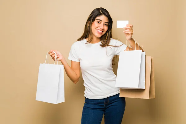 ハッピー美しい若い女性はモックアップTシャツと空白のショッピングバッグを着てクレジットカードで買い物に行く — ストック写真