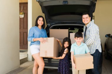 Dört kişilik neşeli, güzel bir aile taşındıktan sonra arabadan yeni evlerine kutu taşıyor.