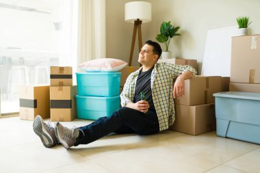 Rahat ve bağımsız bir adam, kutuları açıp yeni bir kiralık eve ya da daireye taşınırken mutlu görünüyor.