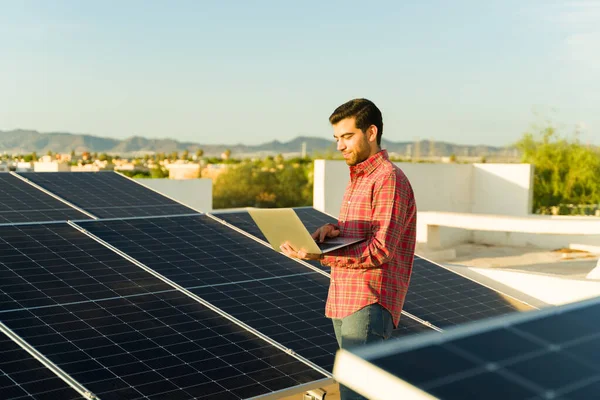 Šťastný Hispánec Kontrolující Energetický Monitor Notebooku Při Použití Solárních Panelů — Stock fotografie