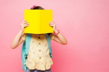 Akıllı küçük çocuk kitap okuyor ve okulda çalışırken bir defterin arkasına saklanıyor. Sırt çantasını fotokopi alanının yanına taşıyor.