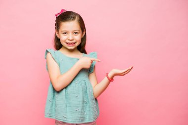 Neşeli bir ilkokul çocuğu elinde sahte bir ürün tutuyor ve stüdyo geçmişine bakarak mutlu görünüyor.