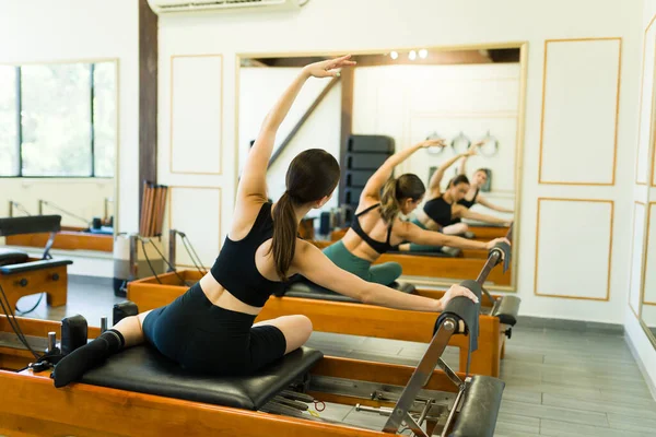 在普拉提健身课上 白种人年轻女子从伸展身体和使用床改革者进行锻炼的角度来看问题 — 图库照片