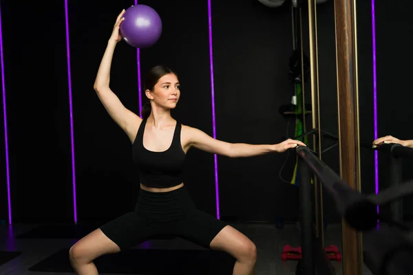 快乐的高加索女人参加了一个野蛮人的课程 她用一个健身球照着镜子 在一个有灯光引导的高端体育馆里 — 图库照片