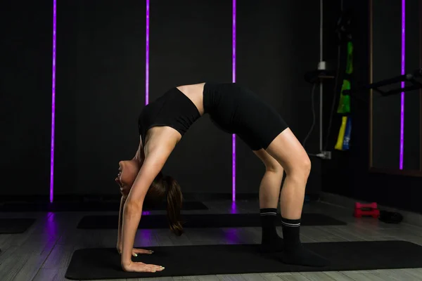 积极健康的年轻女子在深色高端健身房的野蛮运动课上训练她的灵活性 看上去很有弹性 — 图库照片