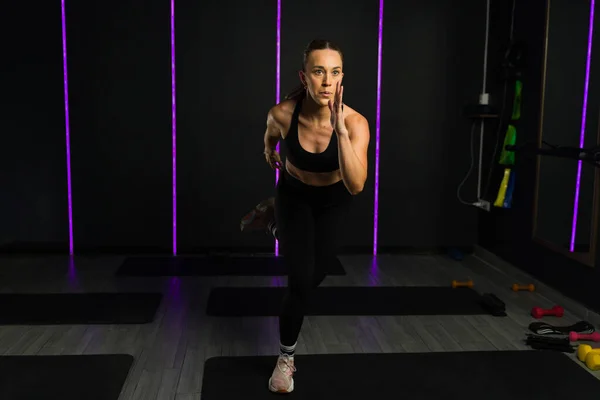 积极健康的年轻女子在黑暗的高端健身房里做有氧运动或交叉训练 有导引照明 — 图库照片