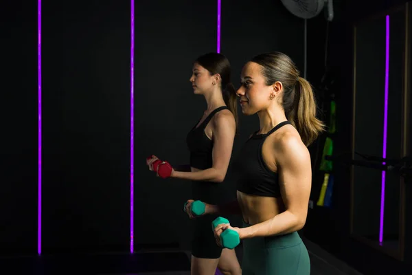 在一个黑暗的高端健身中心的功能性训练课上 强壮健康的女人举起哑铃 — 图库照片
