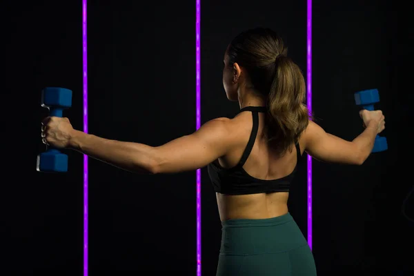 一位体格强壮 体格健壮的年轻女子在一家高档健身房锻炼时 她的哑铃重量显示出她的肌肉后背 同时进行了功能性训练 — 图库照片