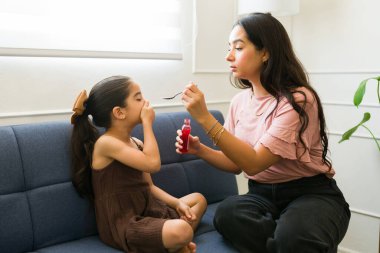 İspanyol anne, hasta çocuğuna öksürük şurubu ya da ilaç verip evde bakıcılık yapıyor.