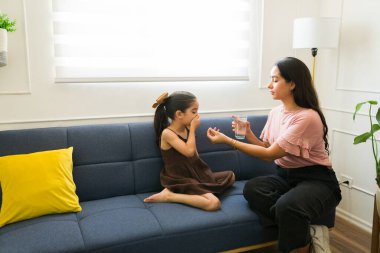 Latin anne, hasta küçük kızına kendini kötü hissedip kanepeye oturup ilaç ve su veriyor. 