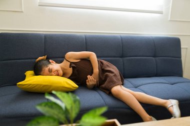 Evde hasta küçük bir kız, kanepede yatarken çok kötü bir mide ağrısından muzdarip. 