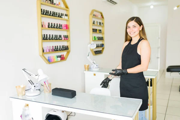 Excited young woman smiling and welcoming a new client to the beauty room for a nail service or manicure
