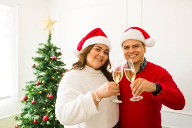 Noel Baba şapkalı güzel bir çiftin portresi. Şampanya içip evde Noel tatili kutluyorlar.