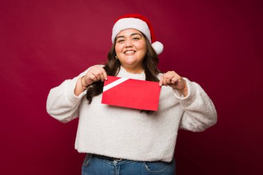 Heyecanlı şişman Meksikalı kadın Noel tatili boyunca kırmızı model bir hediye kartı aldığı için mutlu.