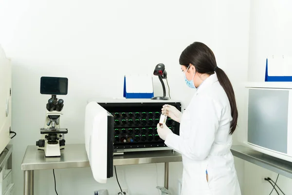 女化学家使用一种将血液样本放入试管中在医学实验室进行培养的培养机 — 图库照片