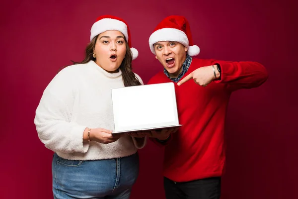 Surprised Hispanic Couple Looking Excited Pointing Blank Screen Laptop Computer — Stock Photo, Image