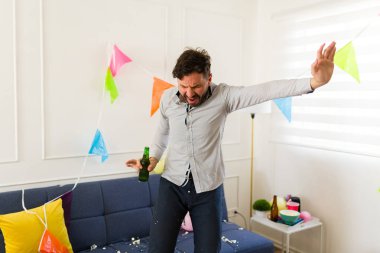 Sabahın erken saatlerinde evde bira ve alkol içerken şarkı söyleyip dans eden sarhoş beyaz adam.