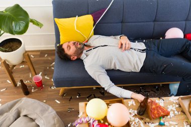 Doğum günü partisini kutlarken çok alkol aldıktan sonra kanepede uyuyan yakışıklı sarhoş adam.