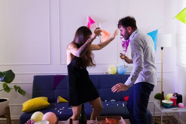 Sarhoş genç bir kadın ve mutlu bir adam parti sırasında eğleniyor alkol içiyor ve birlikte dans ediyorlar. 