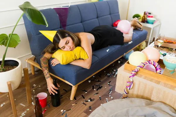 Doğum günü partisinden sonra sabahın erken saatlerinde sarhoş bir şekilde kanepede uyuyan sarhoş genç bir kadın.
