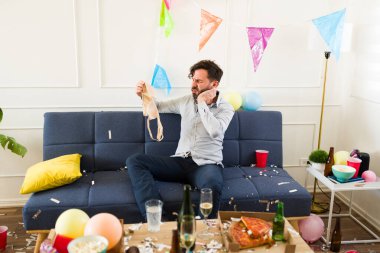 Akşamdan kalma gibi görünen, kafası karışmış, ev partisinde çok alkol içtikten sonra kadın iç çamaşırı tutan beyaz bir adam.