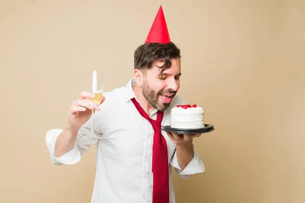 Feliz Homem Comendo Bolo Aniversário Com Chapéu Festa Sorrindo Enquanto — Fotografia de Stock