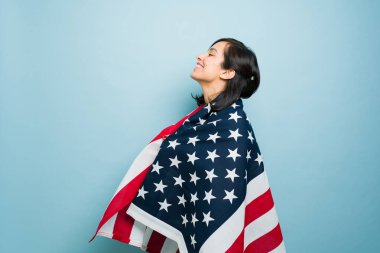 Amerikan bayrağına sarılmış mutlu, beyaz bir kadının profili. Amerikan rüyası için mutlu ve vatansever hissediyor.