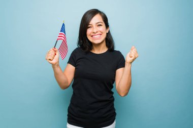 Eğlenceli çekici kadın, elinde bir Amerikan bayrağı tutarken heyecanlı bir şekilde gülüyor. Amerikan rüyası vatanseverlik duygusunu seviyor. 