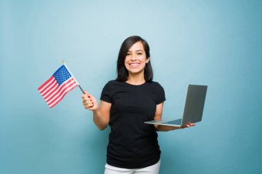 Güzel, beyaz bir kadın, elinde ABD bayrağı tutarken internetten Amerikan vizesi için başvuruyor.