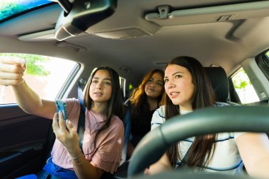 Güzel, mutlu genç kadınlar birlikte seyahat ederken araba sürüyorlar ve GPS 'in yönünü takip ediyorlar. 