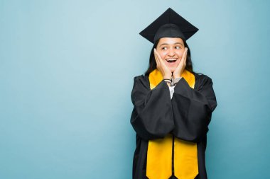 Latin heyecanlı kadın mutluluktan çığlık çığlığa bağırıyor üniversite diplomasını alırken, mezuniyet elbisesini giyip, fotokopi alanı olan mavi bir grupla karşılaşıyor.