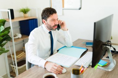 Avukat ya da avukat olarak çalışırken ofisteki bir müşteriyle telefonda konuşan çekici Latin bir profesyonel.