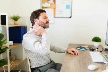 Ofis masasında otururken boynu ağrıyan Latin bir adam ve patron bir sürü iş yapıyor. 