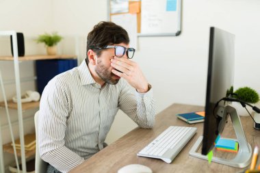 Yorgun girişimci patron ofiste bir sürü iş varken gözlerini ovuşturuyor uykulu hissediyor.