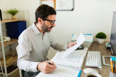 Ofiste muhasebecilik yaparken mutlu bir adam gözlük takıyor ve gülümsüyor. İşinden de keyif alıyor.