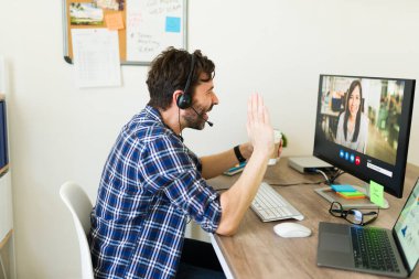 Ofis masasında çalışan neşeli beyaz bir adam video görüşmesi sırasında iş arkadaşından bahsediyor. 