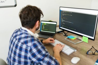 Ofiste yeni yazılım geliştirirken bilgisayarda yeni bir kod yazıp yazan İspanyol programcı.