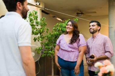 Mutlu İspanyol çift, arka bahçede eğlenmeye hazır arkadaşlarıyla bir akşam yemeği partisine şarap getiriyor.