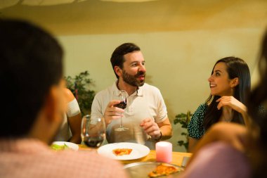 Mutlu İspanyol kadın ve erkek gülerek gece arkadaşlarıyla güzel bir akşam yemeği yerken şarap içiyorlar.