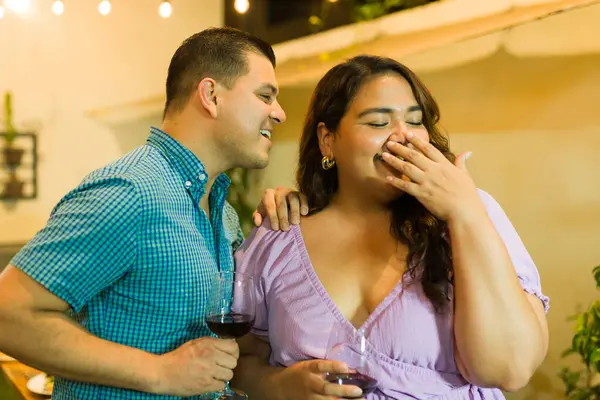 Attractive happy man flirting and talking with a plus size woman having fun together drinking wine during a dinner party