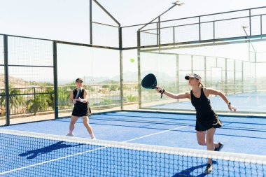 Açık hava kortunda antrenman yaparken padel tenis oynayan aktif fitness bayan arkadaşları