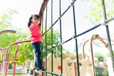 Parkın bahçesinde oyun oynarken gülümseyen gözlüklü sevimli küçük çocuk.